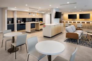 a lobby with tables and chairs and a kitchen at TownePlace Suites by Marriott West Kelowna in West Kelowna