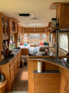 uma cozinha com armários de madeira e uma sala de estar num trailer em Stybeck Farm em Thirlmere