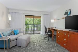 a hotel room with a desk and a living room at Courtyard by Marriott Monroe Airport in Monroe