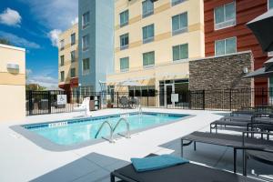 a swimming pool with tables and chairs next to a building at Fairfield Inn & Suites by Marriott Shelby in Shelby