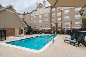 a swimming pool with chairs next to a building at Residence Inn by Marriott Charlotte Piper Glen in Charlotte