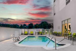 a swimming pool on the roof of a building with a sunset at SpringHill Suites by Marriott Charlotte Airport Lake Pointe in Charlotte