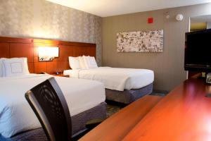 a hotel room with two beds and a desk at Courtyard Waterbury Downtown in Waterbury