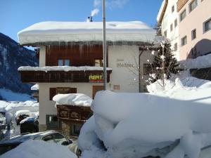 um edifício coberto de neve ao lado de um parque de estacionamento em Haus Wechner em Kappl