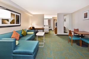 Habitación de hotel con sofá azul y mesa en Springhill Suites by Marriott Chicago Elmhurst Oakbrook Area, en Elmhurst