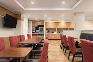 a restaurant with tables and chairs and a kitchen at TownePlace Suites by Marriott Janesville in Janesville