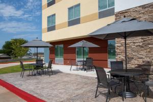 a group of tables and chairs with umbrellas in front of a building at Fairfield Inn & Suites Duncan in Duncan
