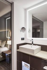 bagno con lavandino bianco e specchio di Courtyard by Marriott Wolfsburg a Wolfsburg