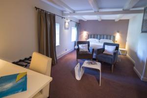 a bedroom with a bed and two chairs and a table at Hôtel Restaurant Les Alisiers in Lapoutroie