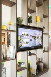 a living room with a tv on a wall with shelves at Courtyard by Marriott Wolfsburg in Wolfsburg