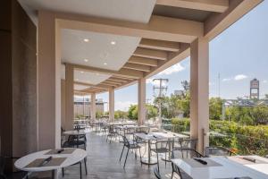 una fila de mesas y sillas en un restaurante en AC Hotel by Marriott Guadalajara Expo en Guadalajara