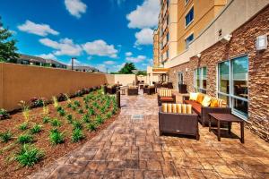 a patio with chairs and tables outside of a building at Courtyard by Marriott Westbury Long Island in Westbury