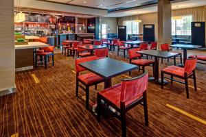 a restaurant with tables and red chairs and a bar at Courtyard by Marriott Westbury Long Island in Westbury