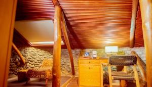 Trois Ore Residences & Green Earth Bistro في إيبادان: غرفة بها مكتب وكراسي وسقف خشبي