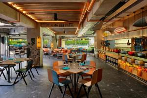 a restaurant with tables and chairs in a room at Aloft Bali Kuta at Beachwalk in Kuta