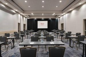 a conference room with tables and chairs and a screen at Marriott Greensboro Downtown in Greensboro