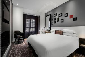 una camera d'albergo con un letto bianco e una sedia di Protea Hotel Fire & Ice! by Marriott Pretoria Menlyn a Pretoria