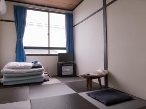 a room with a bed and a window and a table at Wakatake in Katsuura