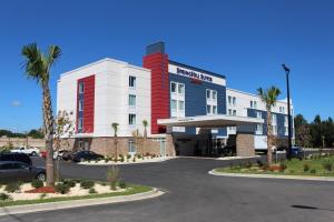 a hotel with a red and white building with a parking lot at SpringHill Suites by Marriott Sumter in Sumter
