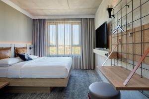 um quarto de hotel com uma cama e uma televisão em Moxy Cologne Muelheim em Colônia