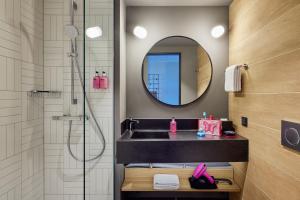 a bathroom with a sink and a shower with a mirror at Moxy Cologne Muelheim in Cologne