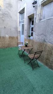 2 chaises et une table sur une terrasse avec de l'herbe verte dans l'établissement Résidence du Palais, à Nevers