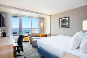 エリーにあるCourtyard by Marriott Erie Bayfrontのベッド、デスク、ソファが備わるホテルルームです。