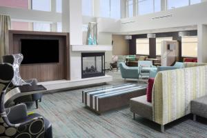 Residence Inn by Marriott Denver Southwest/Littleton في ليتلتون: لوبي فيه موقد وكراسي وتلفزيون