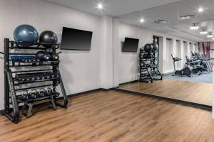 a room with a gym with exercise equipment and mirrors at Courtyard by Marriott East Lansing Okemos in Okemos
