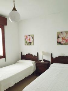 a bedroom with two beds and two pictures on the wall at Casa Vasca in Llanes