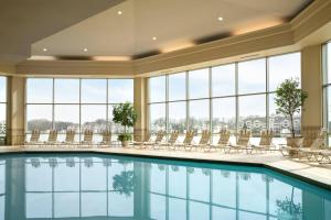 a swimming pool in a hotel with chairs and windows at Marriott Indianapolis North in Indianapolis
