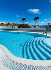 einen Pool mit blauem Wasser und Palmen in der Unterkunft Peace and View Apartment Puerto Rico in Puerto Rico de Gran Canaria