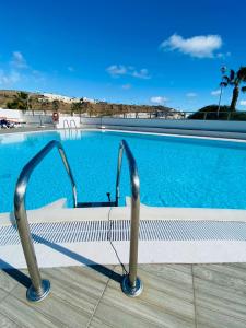 a swimming pool with a bench in front of it at Peace and View Apartment Puerto Rico in Puerto Rico de Gran Canaria