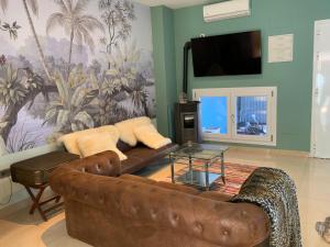 un soggiorno con divano in pelle marrone e TV a schermo piatto di Nacaren Cullera a Cullera