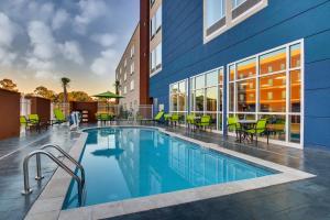 uma piscina com mesas e cadeiras ao lado de um edifício em SpringHill Suites by Marriott Gulfport I-10 em Gulfport