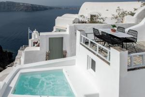 balcón con mesa y piscina en Ambi Villas Santorini en Oia