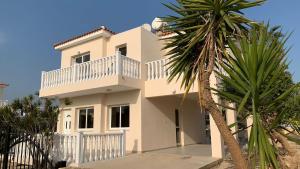 a white house with a balcony and a palm tree at Sunrise Villa 11 in Ayia Thekla in Ayia Napa