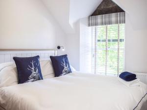 a bedroom with a white bed with blue pillows and a window at Ivy Cottage in Falkland