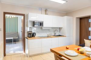 a kitchen with white cabinets and a wooden table at Apartament na deptaku, MyWeek in Polanica-Zdrój