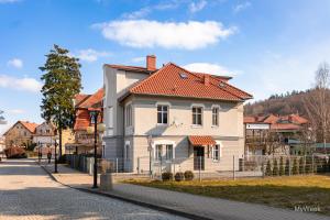 une maison blanche avec un toit orange dans une rue dans l'établissement Apartament na deptaku, MyWeek, à Polanica-Zdrój