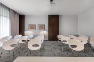 une salle de conférence avec des tables et des chaises blanches dans l'établissement AC Hotel Coslada Aeropuerto by Marriott, à Coslada