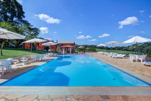 einen Pool mit Stühlen und Sonnenschirmen in einem Resort in der Unterkunft Filimahalo Hotel in Serra Negra