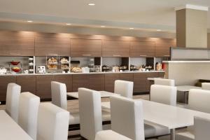 uma sala de jantar com mesas brancas e cadeiras brancas em TownePlace Suites by Marriott Outer Banks Kill Devil Hills em Kill Devil Hills