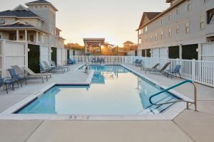 a swimming pool at a resort with chairs and a building at TownePlace Suites by Marriott Outer Banks Kill Devil Hills in Kill Devil Hills