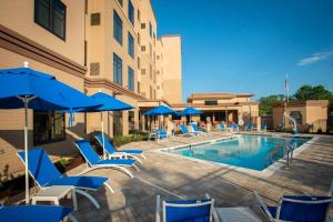 a swimming pool with chairs and umbrellas next to a building at Residence Inn by Marriott Pensacola Airport/Medical Center in Pensacola