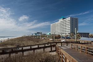 a building on the beach next to a boardwalk at Courtyard Carolina Beach in Carolina Beach