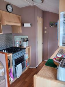 a kitchen with a stove and a clock on the wall at Melody Brooks Caravan Park in Portknockie