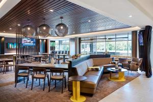 SpringHill Suites Kansas City Airport في كانساس سيتي: مطعم فيه كنب وطاولات وكراسي
