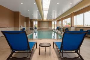 a swimming pool with two chairs and a table at SpringHill Suites Kansas City Airport in Kansas City