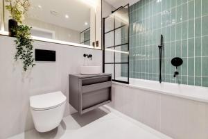 a bathroom with a toilet and a green tile wall at Luxury Harrow Wembley Apartment in Harrow